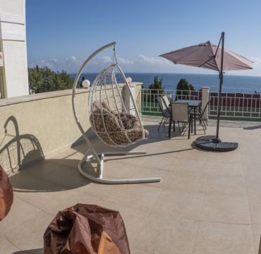 Кресло, кресло-мешок и столик с зонтиком на террасе гостиницы Вилла Мира в Алуште в Крыму